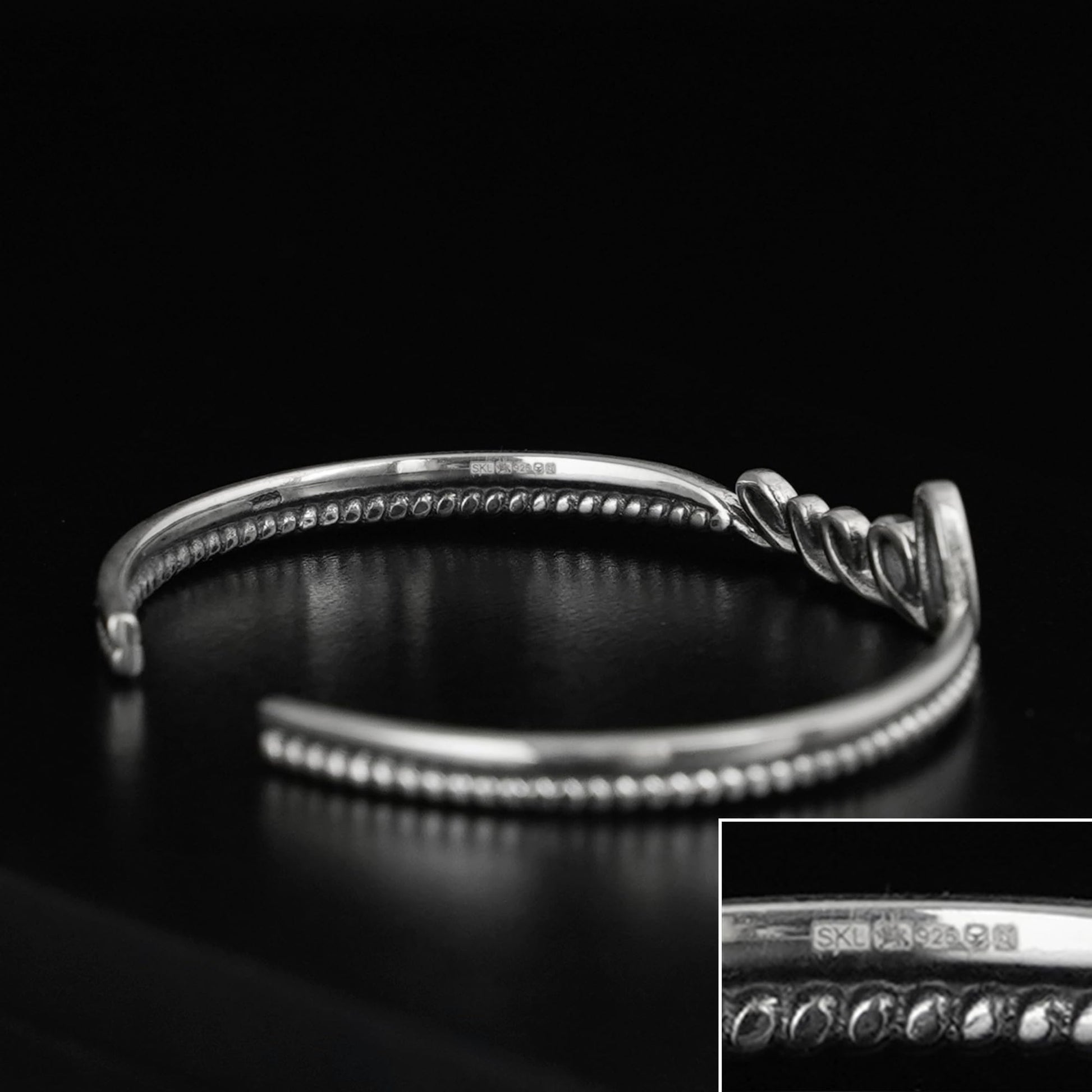 Silver rope-cuff bracelet with beaded ridges and a knot charm detail.
