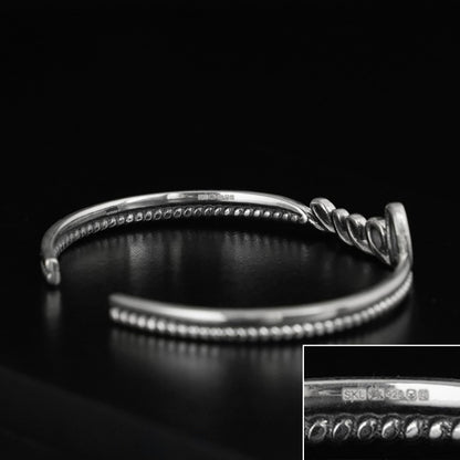 Silver rope-cuff bracelet with beaded ridges and a knot charm detail.
