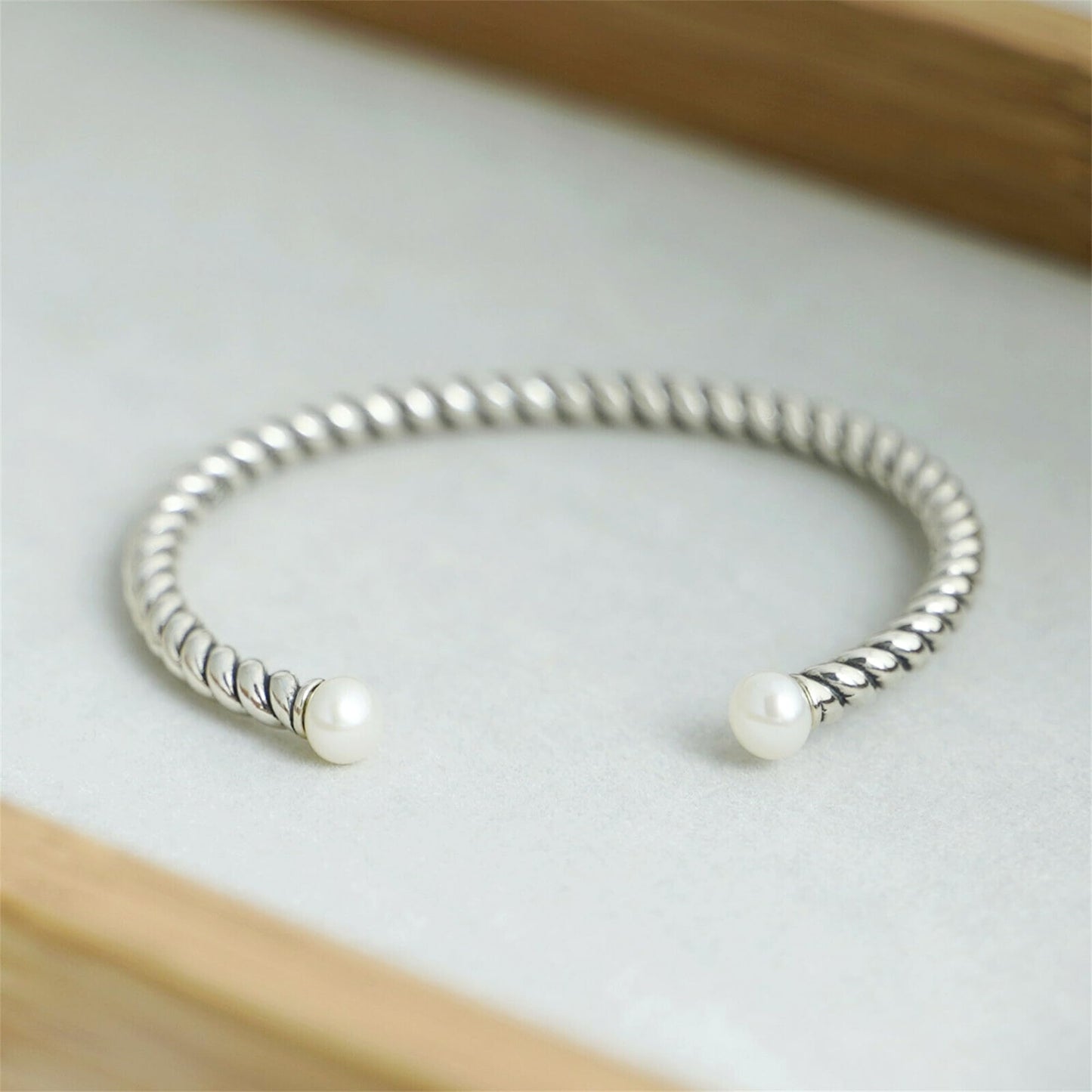Pearl twisted torque bangle with twisted silver cuff and two white pearls on ends.