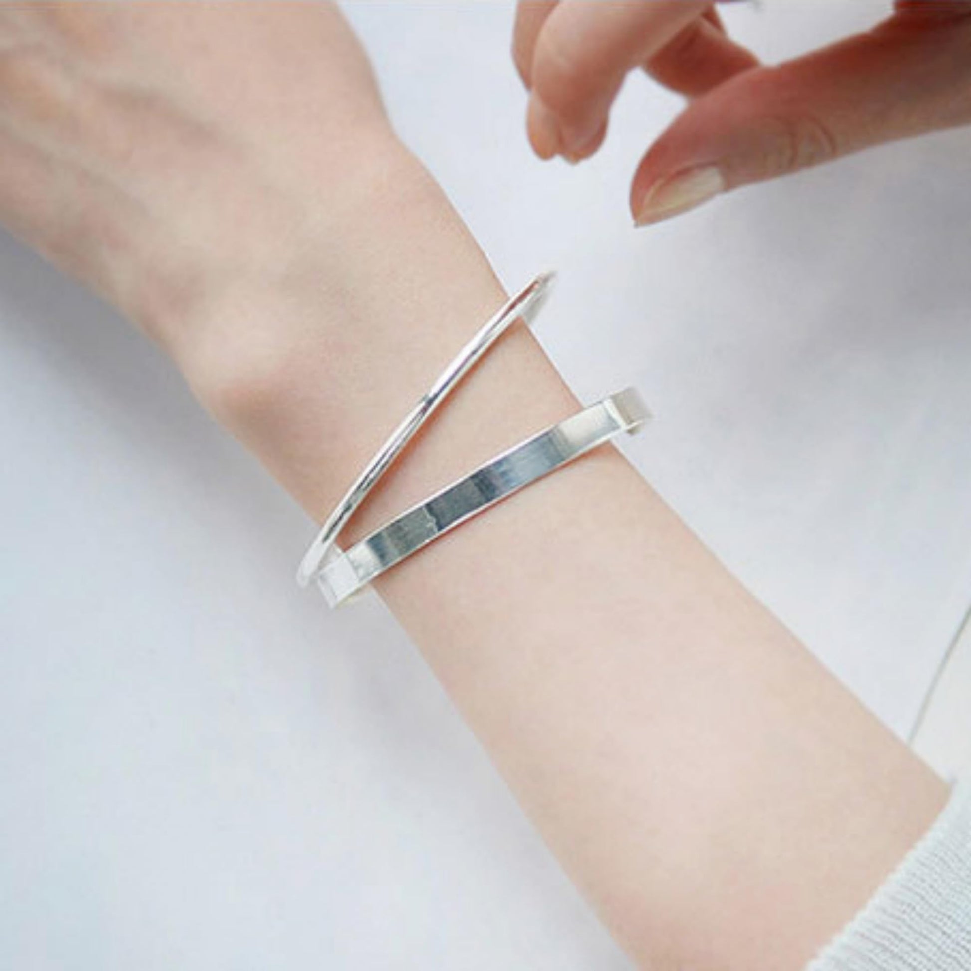 Polished cuff bangle on wrist, silver-tone wide band open cuff