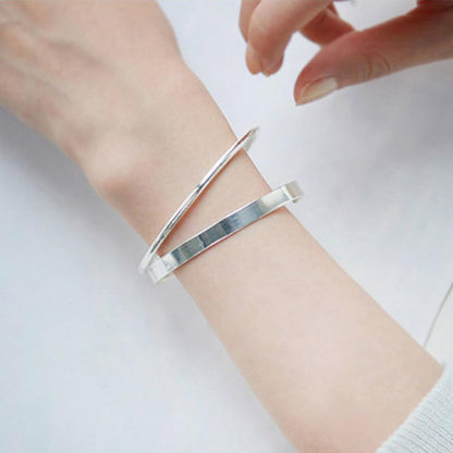 Polished cuff bangle on wrist, silver-tone wide band open cuff