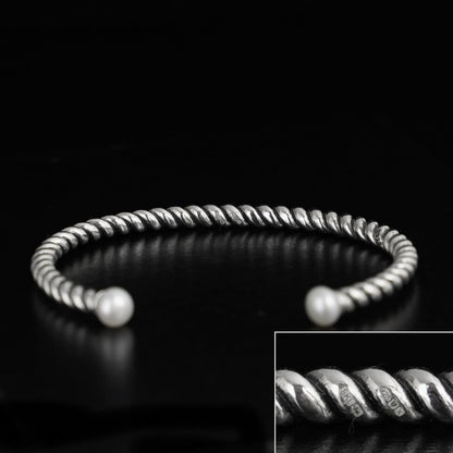 Pearl twisted torque bangle with ridged silver wire and two white pearl tips.