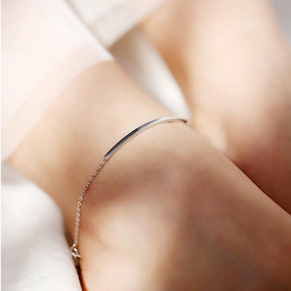 Silver curved tube bar anklet on ankle