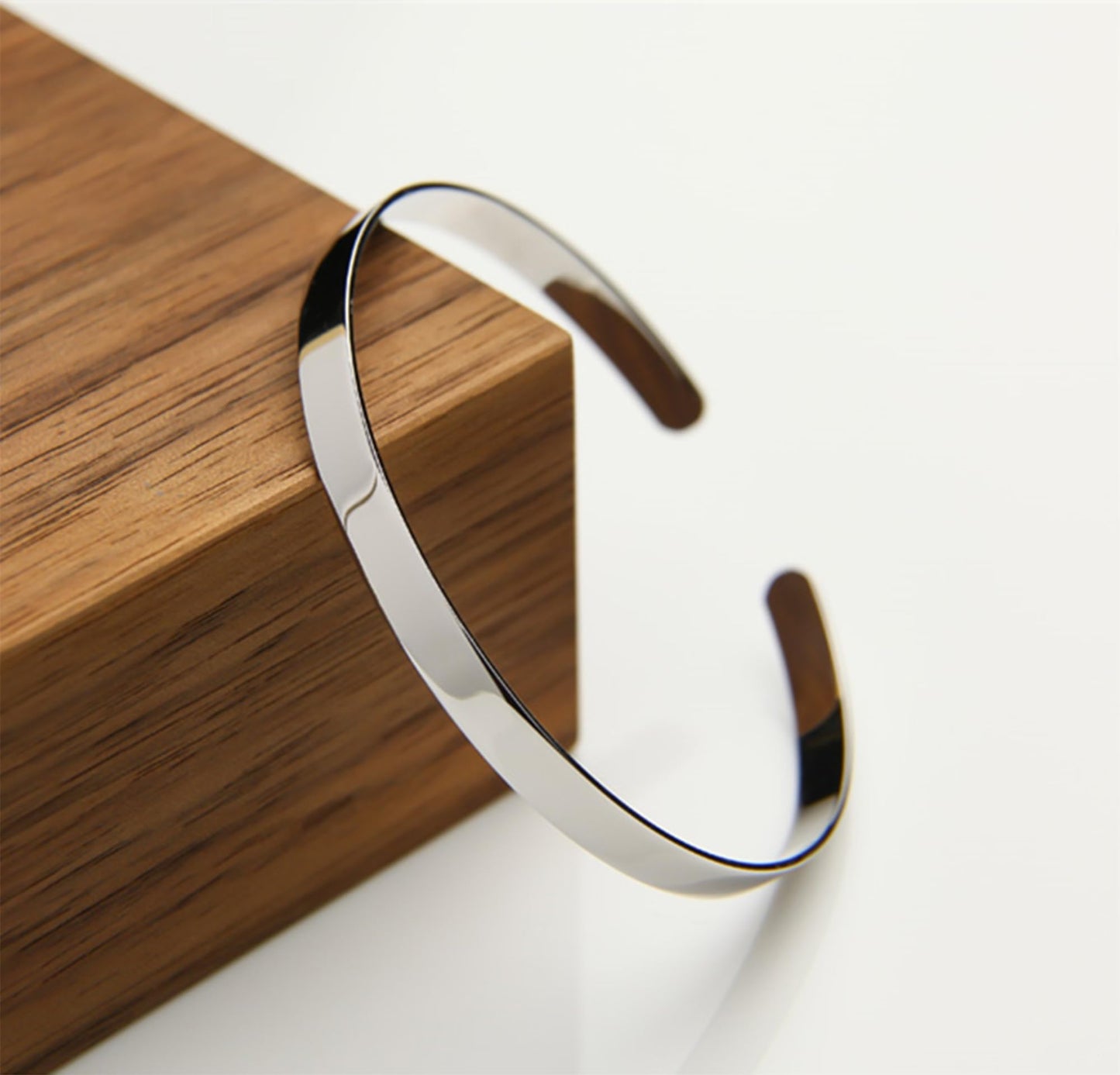 Polished cuff bangle, silver-tone open cuff bracelet on wooden surface