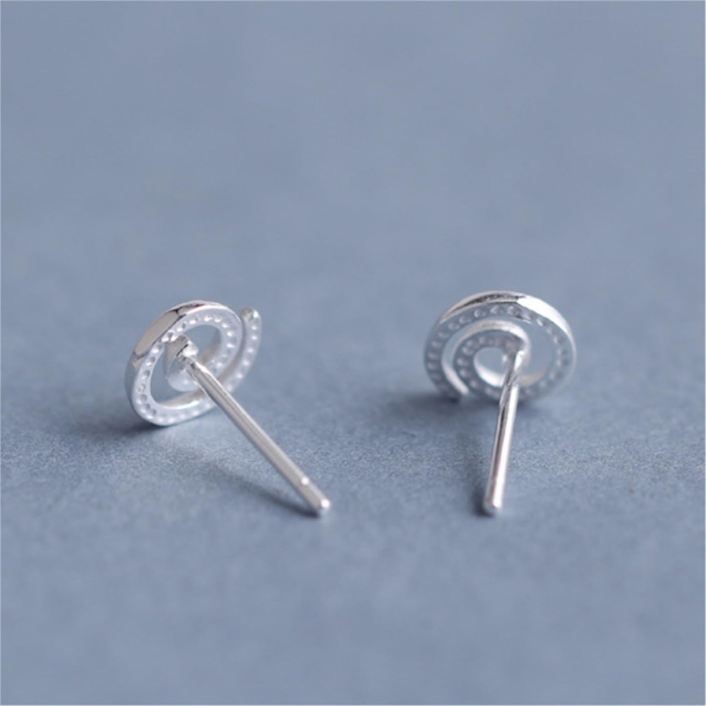Silver spiral swirl stud earrings, round swirl face with visible straight posts.