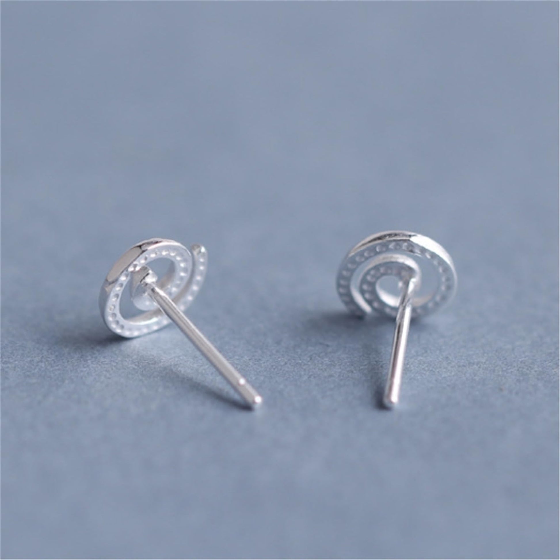 Silver spiral swirl stud earrings, round swirl face with visible straight posts.