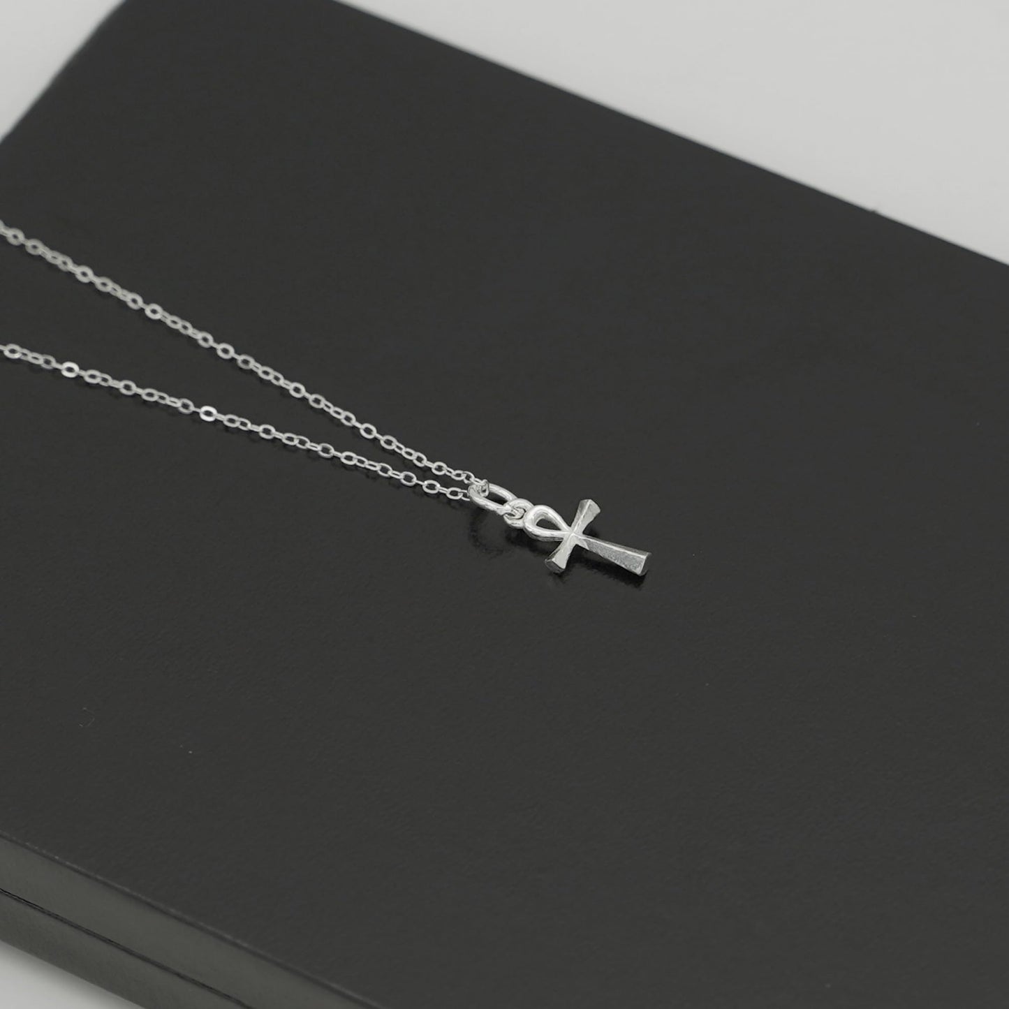 Silver-tone ankh cross pendant on chain, angled view of charm