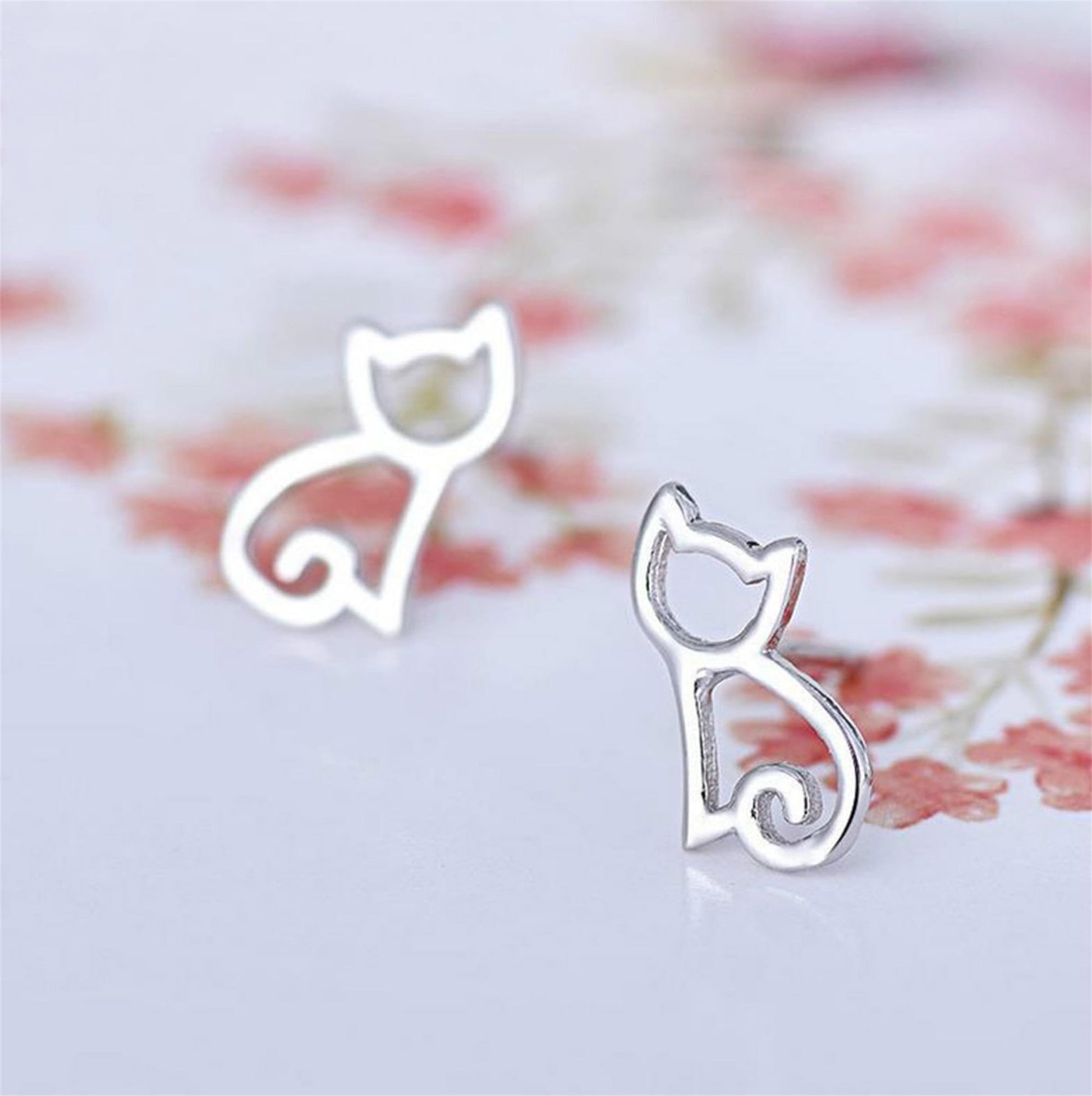 Silver-tone cat outline stud earrings with small curled tail details
