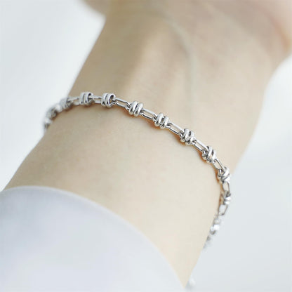 Silver-tone oval curb bracelet on wrist with clasp and repeating link pattern