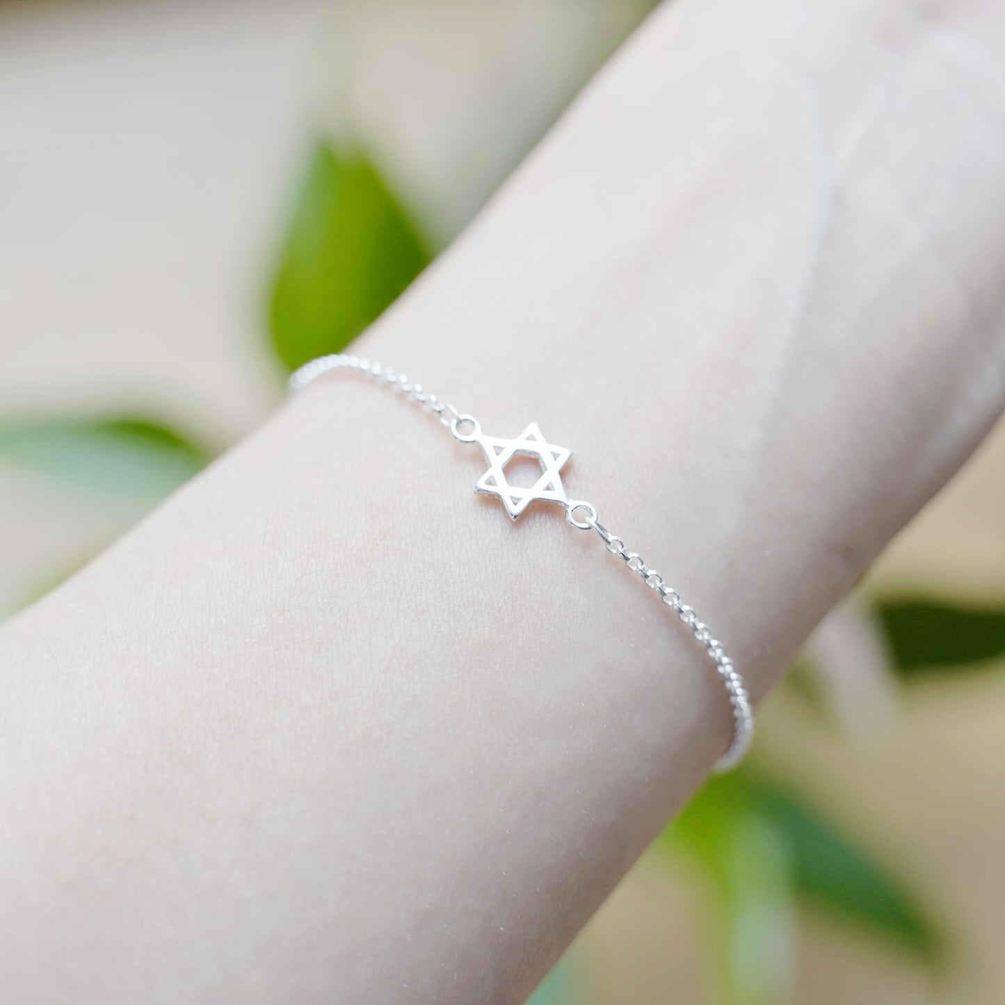 Silver-tone Star of David charm bracelet on wrist with linked bead chain