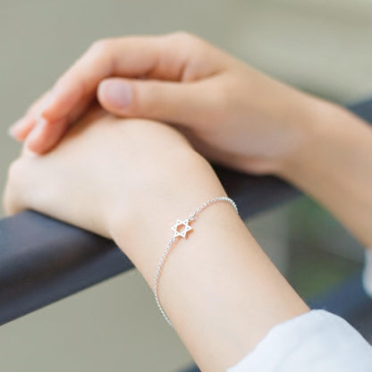 Silver-tone Star of David charm bracelet on wrist with star pendant