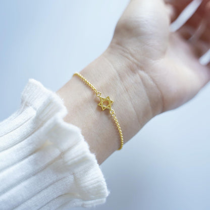 Gold-tone Star of David charm bracelet on wrist with star pendant centerpiece