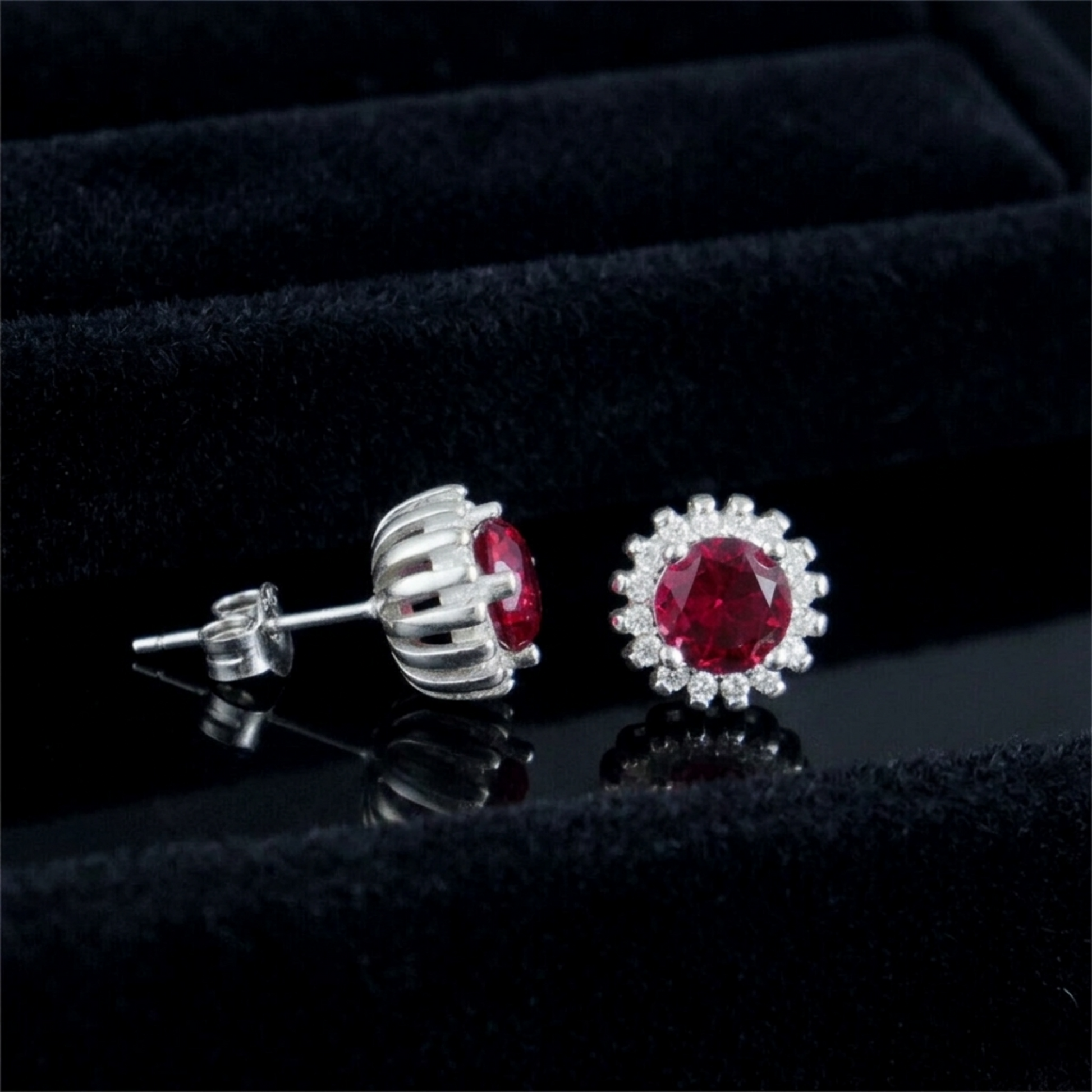 Silver stud earrings with round red gemstone and halo of clear stones, side view
