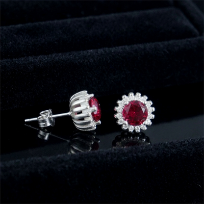 Silver stud earrings with round red gemstone and halo of clear stones, side view