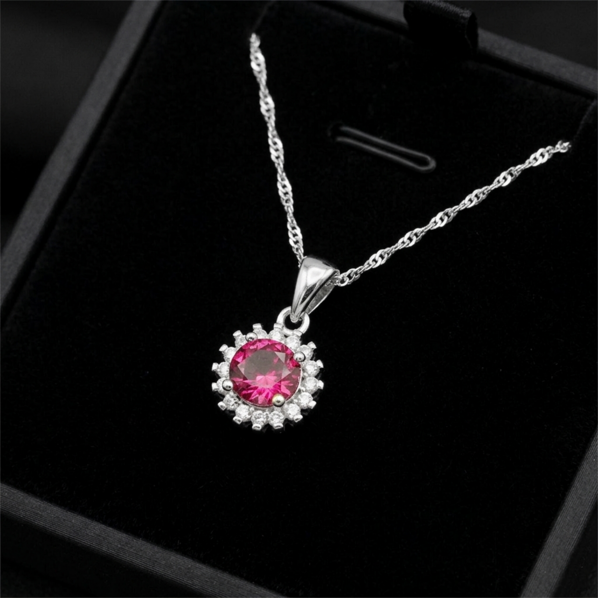 Silver necklace pendant with round red gemstone cluster and clear stone halo