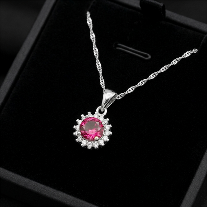 Silver necklace pendant with round red gemstone cluster and clear stone halo