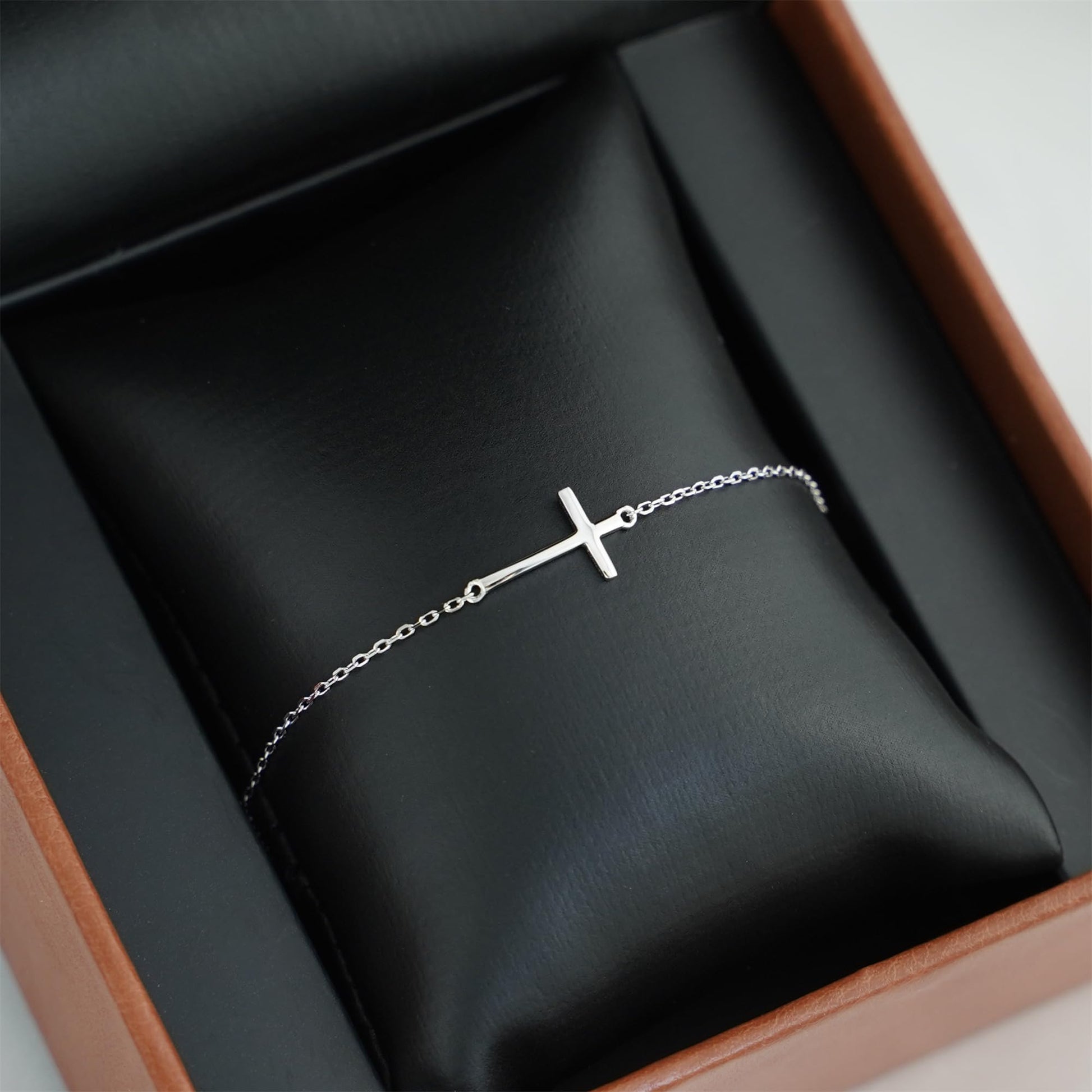Silver-tone side cross anklet bracelet laid in a jewelry box.