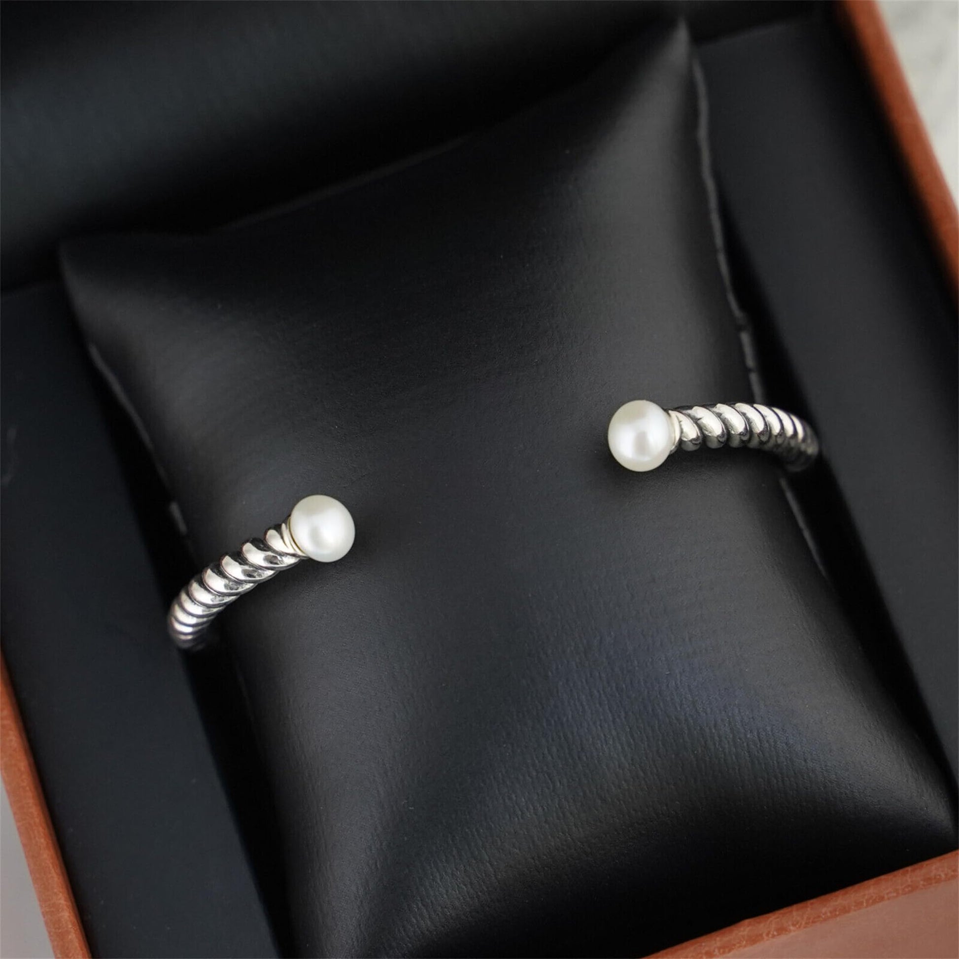 Pearl twisted torque bangle on display cushion with two white pearl end beads.