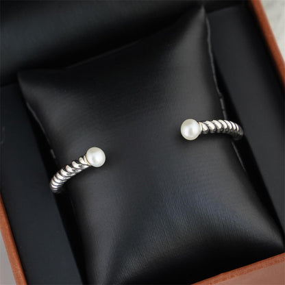 Pearl twisted torque bangle on display cushion with two white pearl end beads.