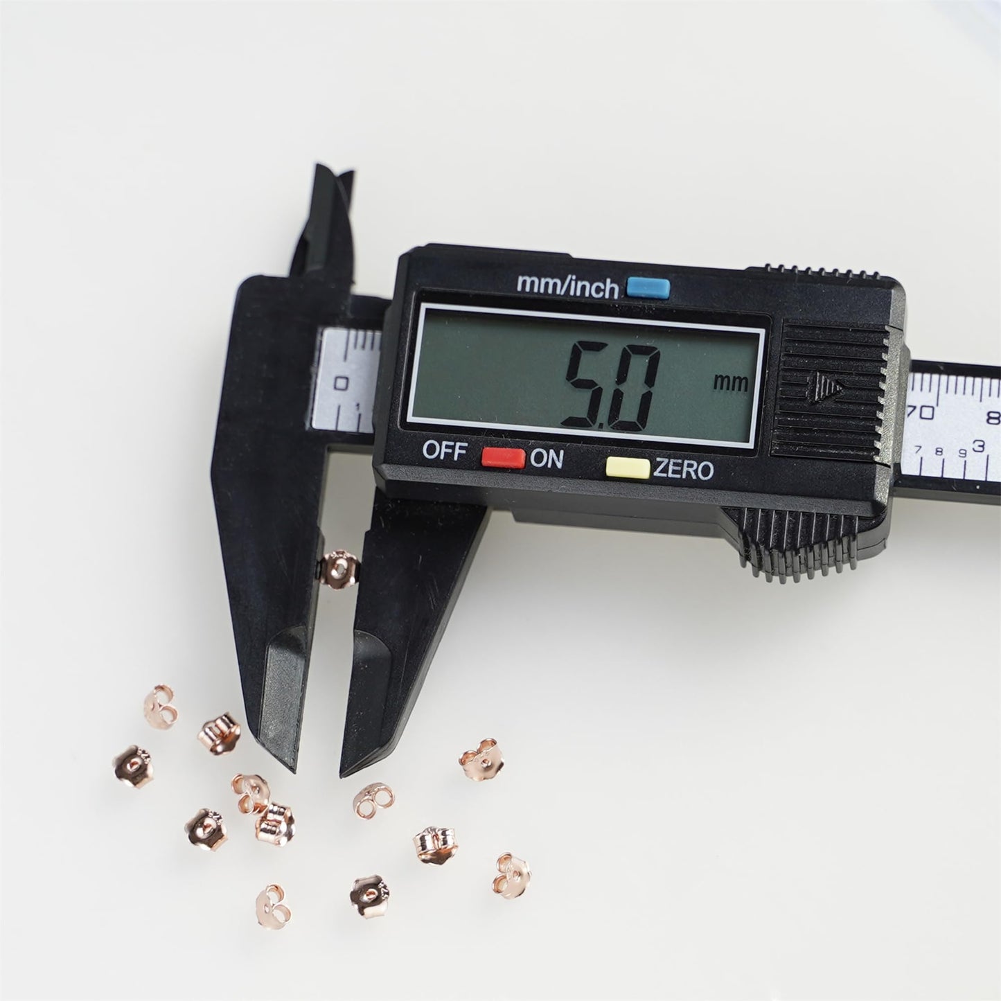 5mm rose gold butterfly earring backs next to a caliper measure