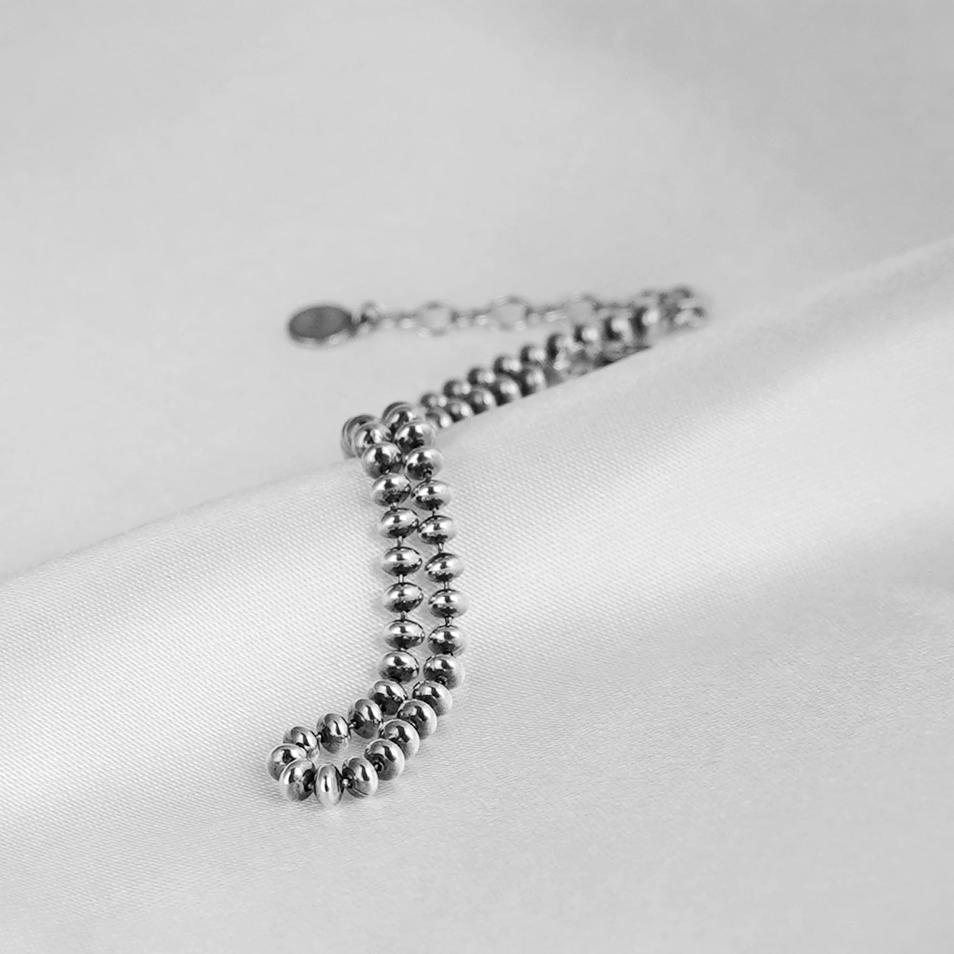 Silver-tone flat bead bracelet detail with round clasp and bead links
