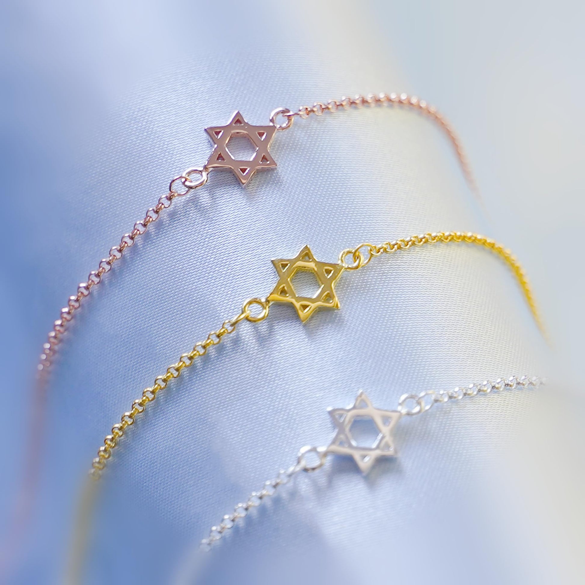 Star of David charm bracelets set with rose gold, gold, and silver star pendants
