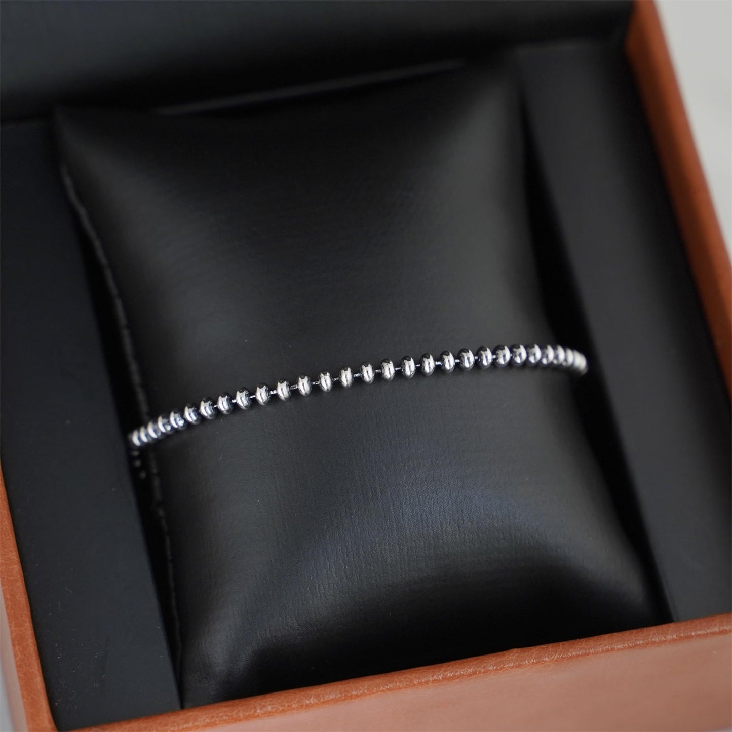Silver-tone flat bead bracelet displayed in jewelry box with beaded links
