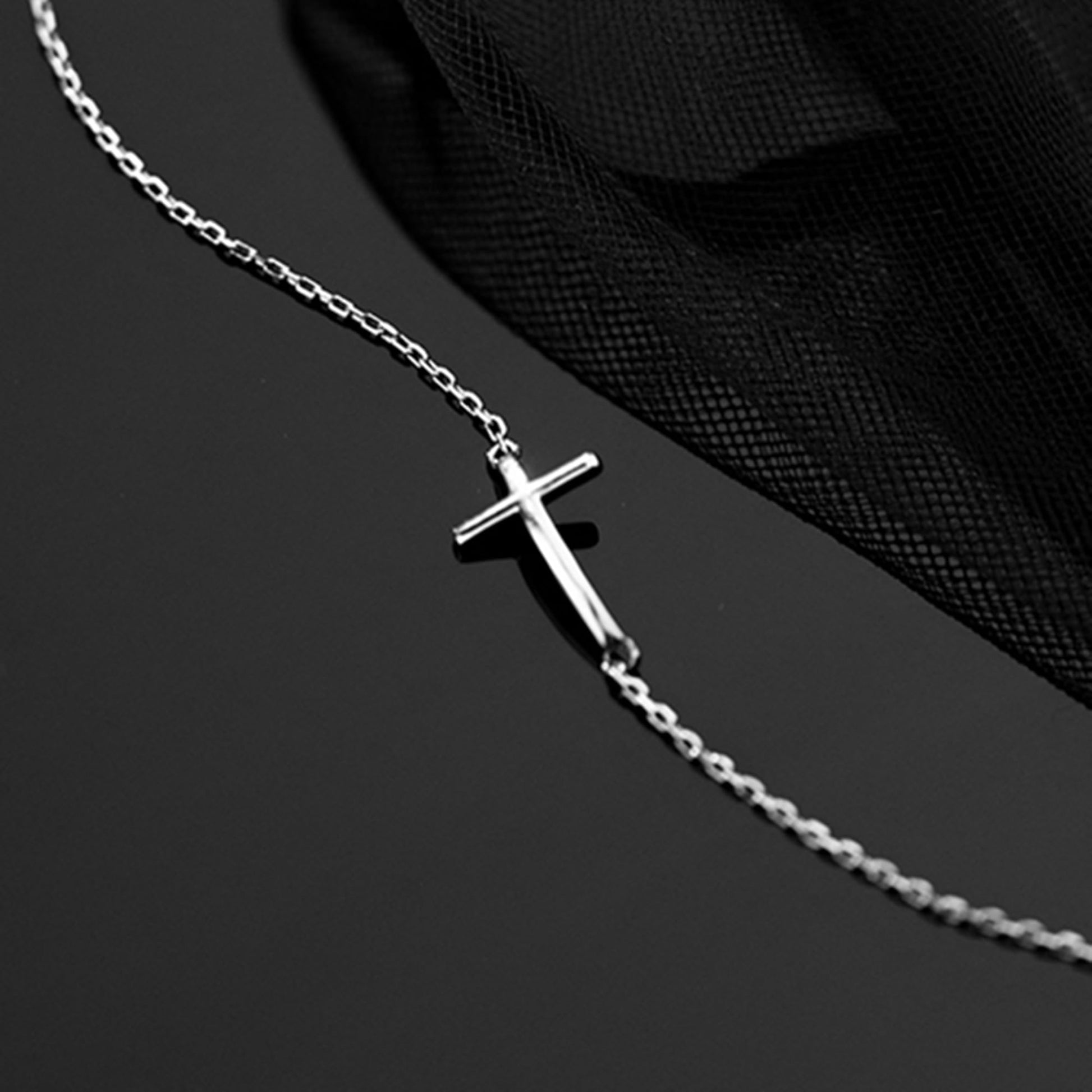 Silver-tone chain anklet bracelet with sideways cross charm close-up.