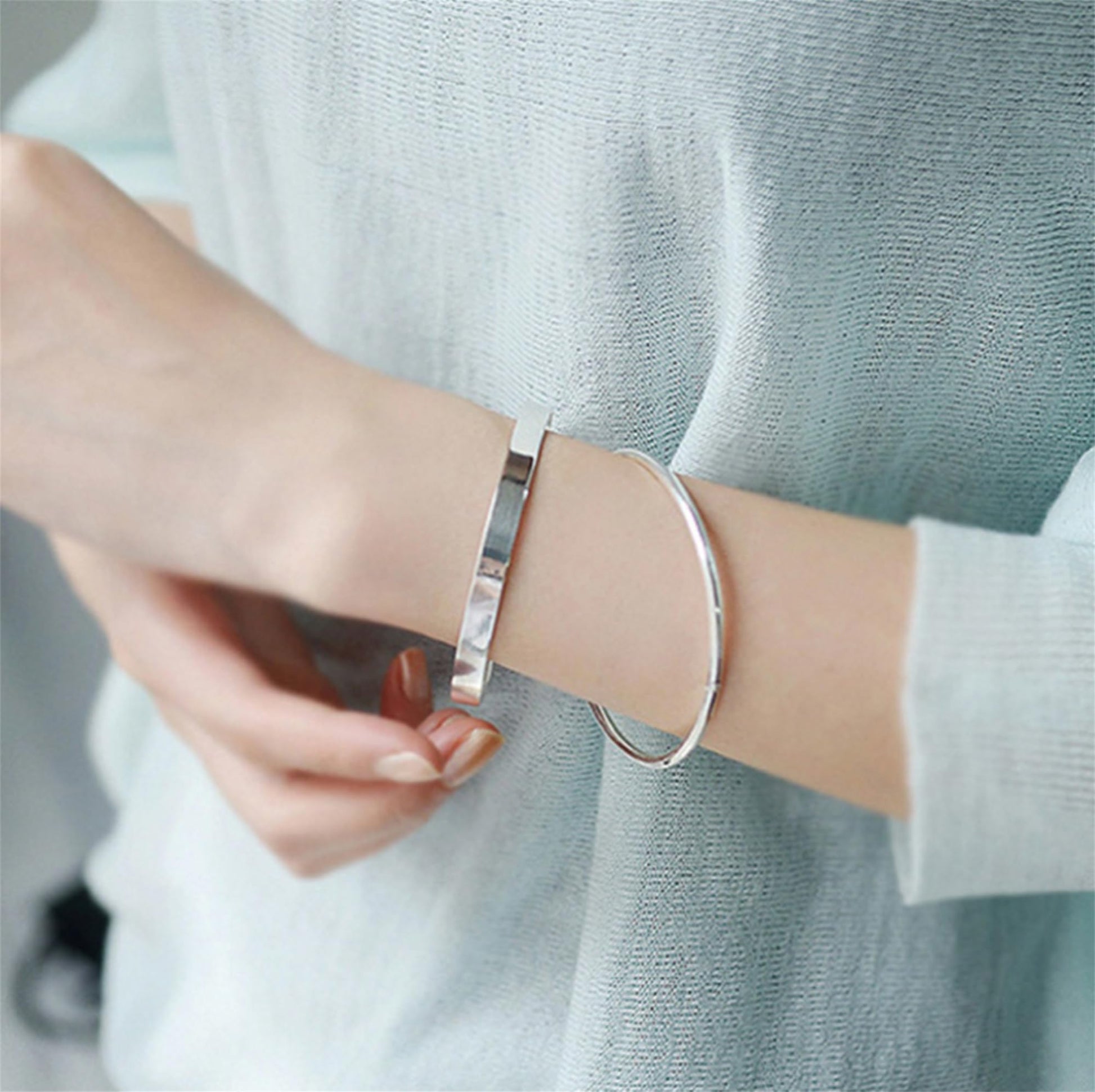 Polished cuff bangle on wrist, silver-tone open cuff bracelet