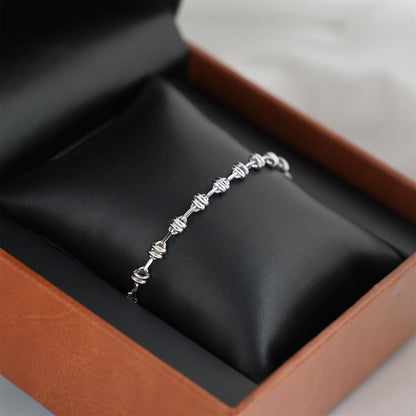 Silver-tone oval curb chain bracelet on black display cushion in a box