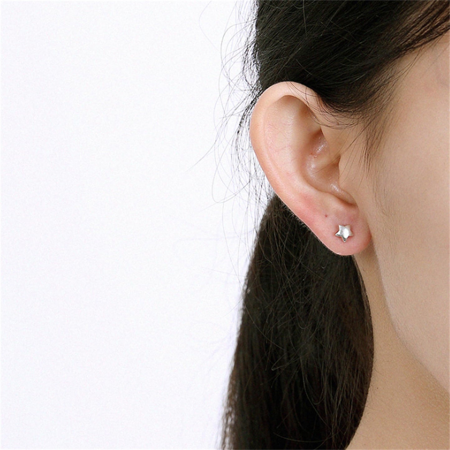 Five-point star stud earrings on ear, silver-tone, small pair