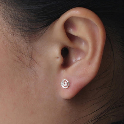 Silver spiral swirl stud earring on ear, small curled swirl design.