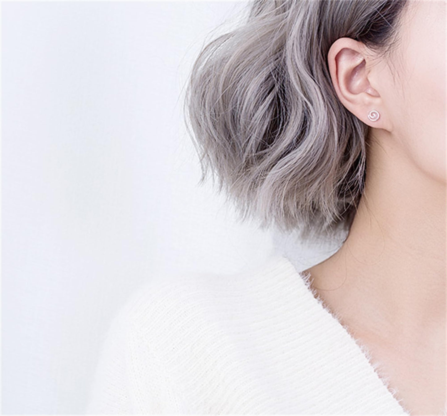 Silver spiral swirl stud earring on ear, curled swirl detail in silver tone.