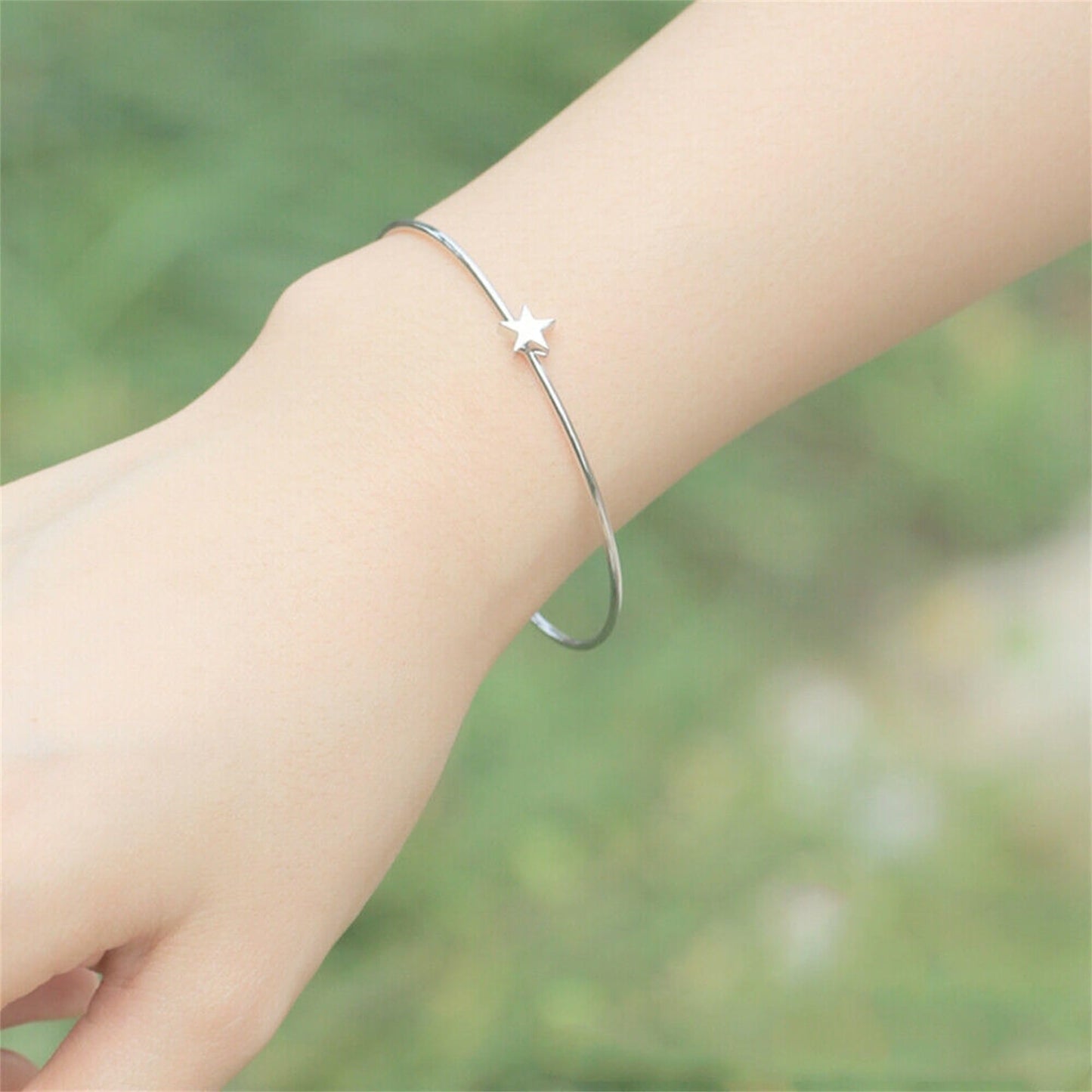 Silver star charm torque bangle on wrist