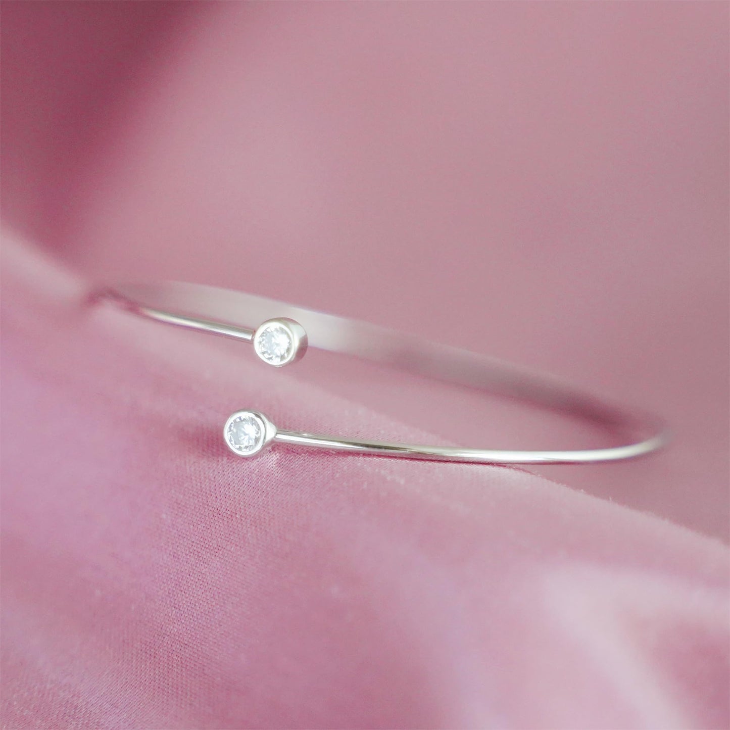 Silver-tone torque bangle detail with two round CZ stones on slim bar