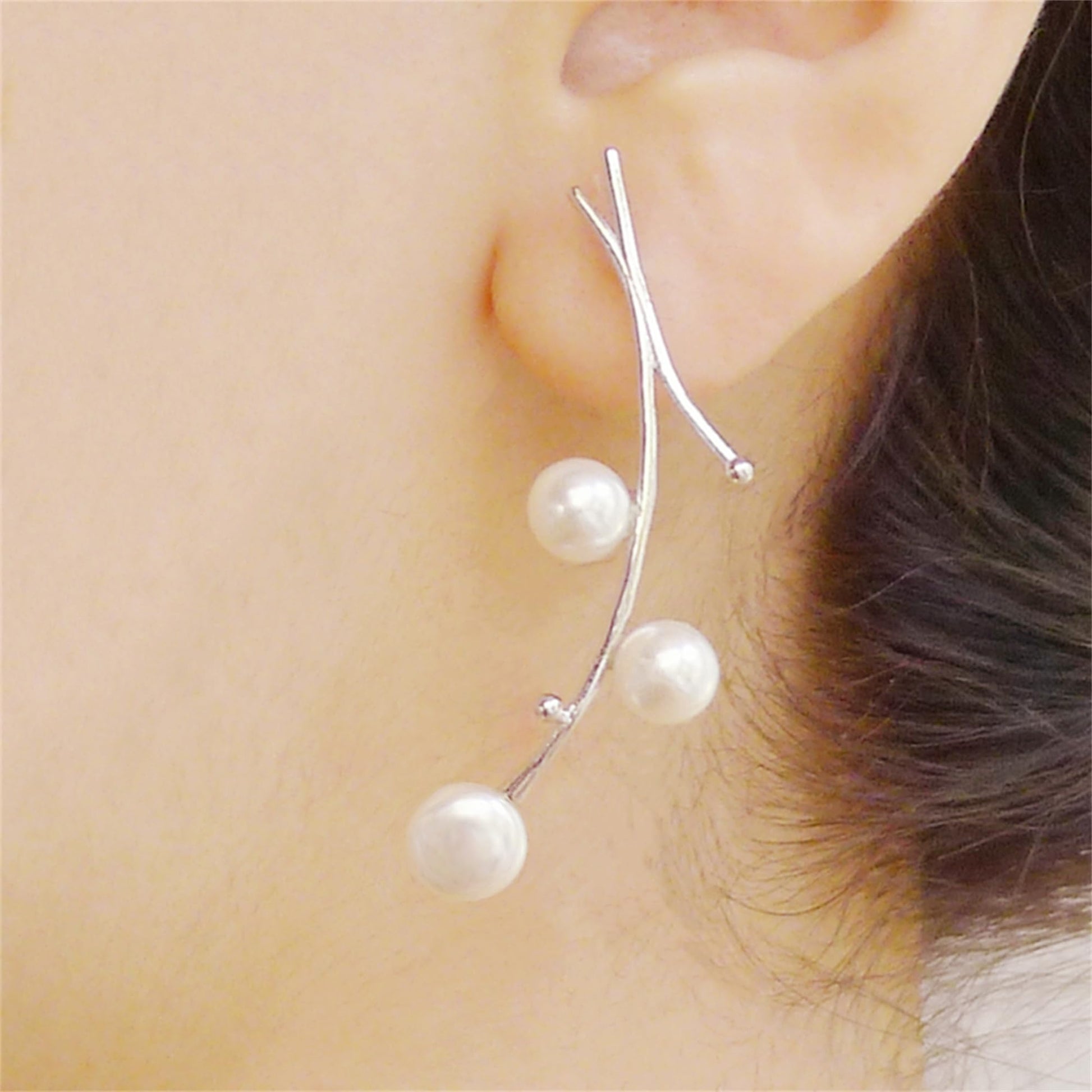 White pearl drop earrings on thin silver hooks with three dangling pearls