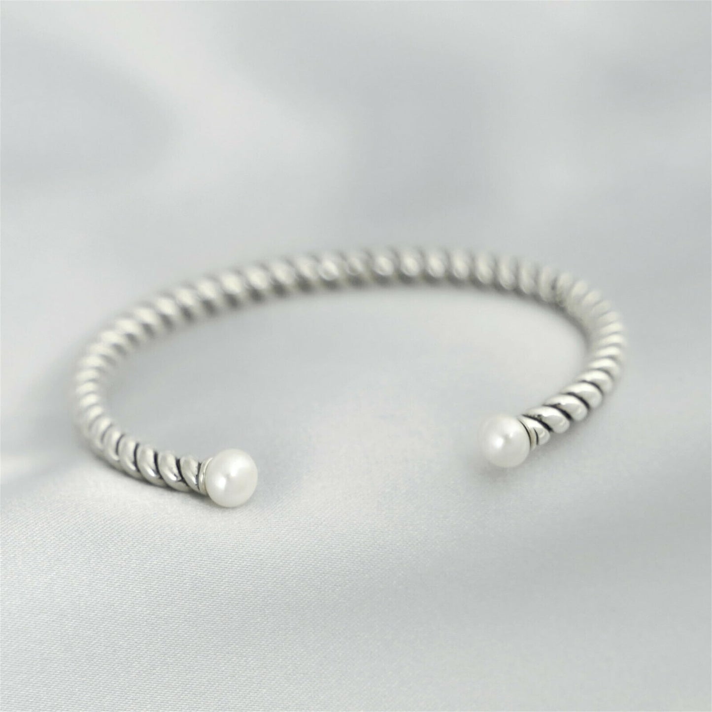 Pearl twisted torque bangle with twisted silver band and two white pearl beads.