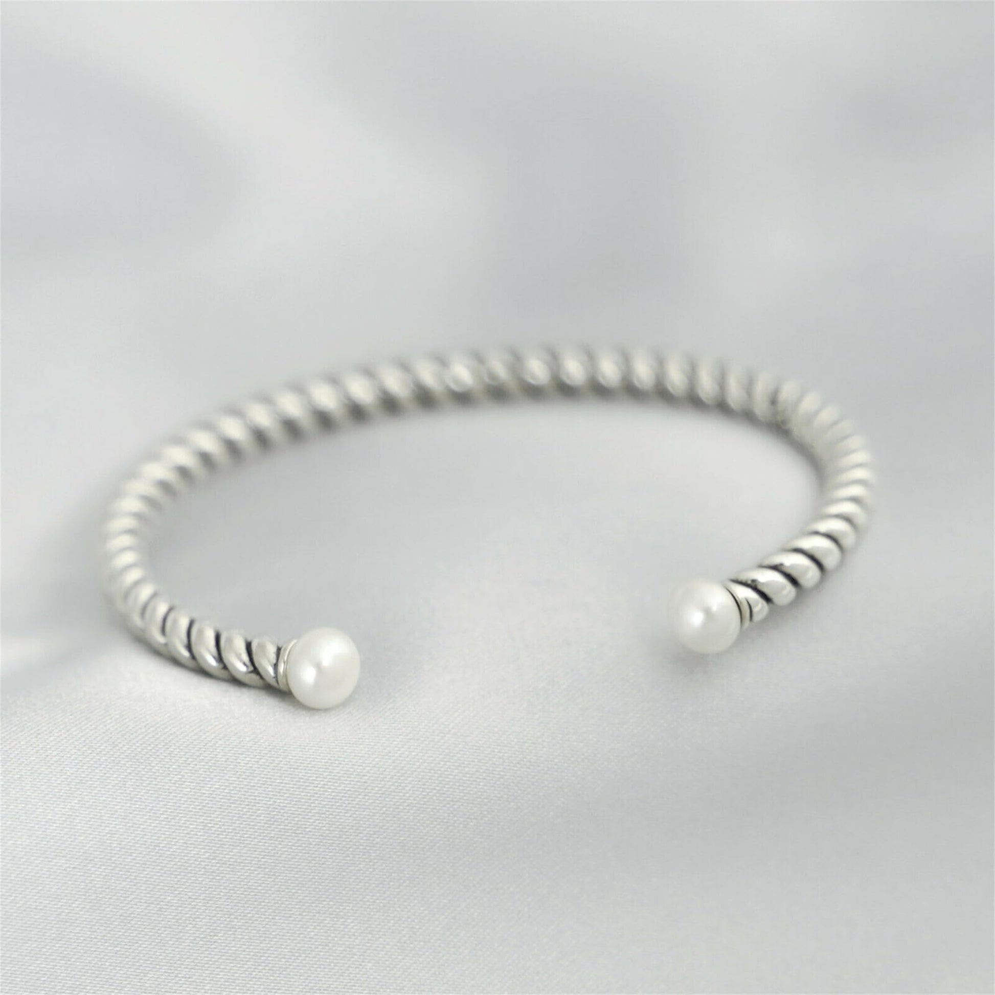 Pearl twisted torque bangle with twisted silver band and two white pearl beads.