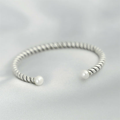 Pearl twisted torque bangle with twisted silver band and two white pearl beads.