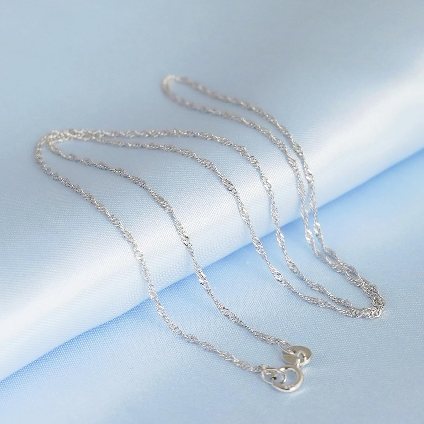Rhodium twisted chain necklace featuring a small clover charm pendant