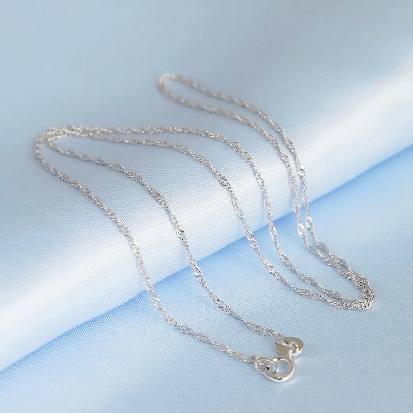 Rhodium twisted chain necklace featuring a small clover charm pendant