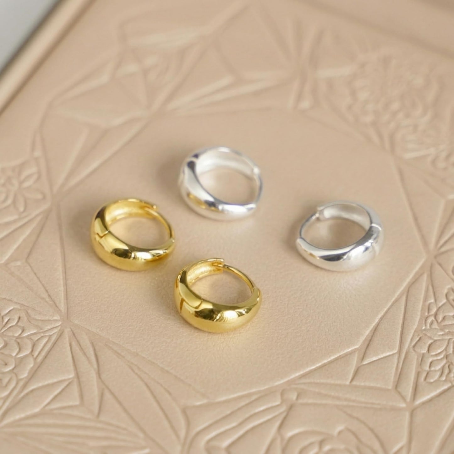 Gold and silver teardrop hoop huggie earrings set, three gold and one silver pair.