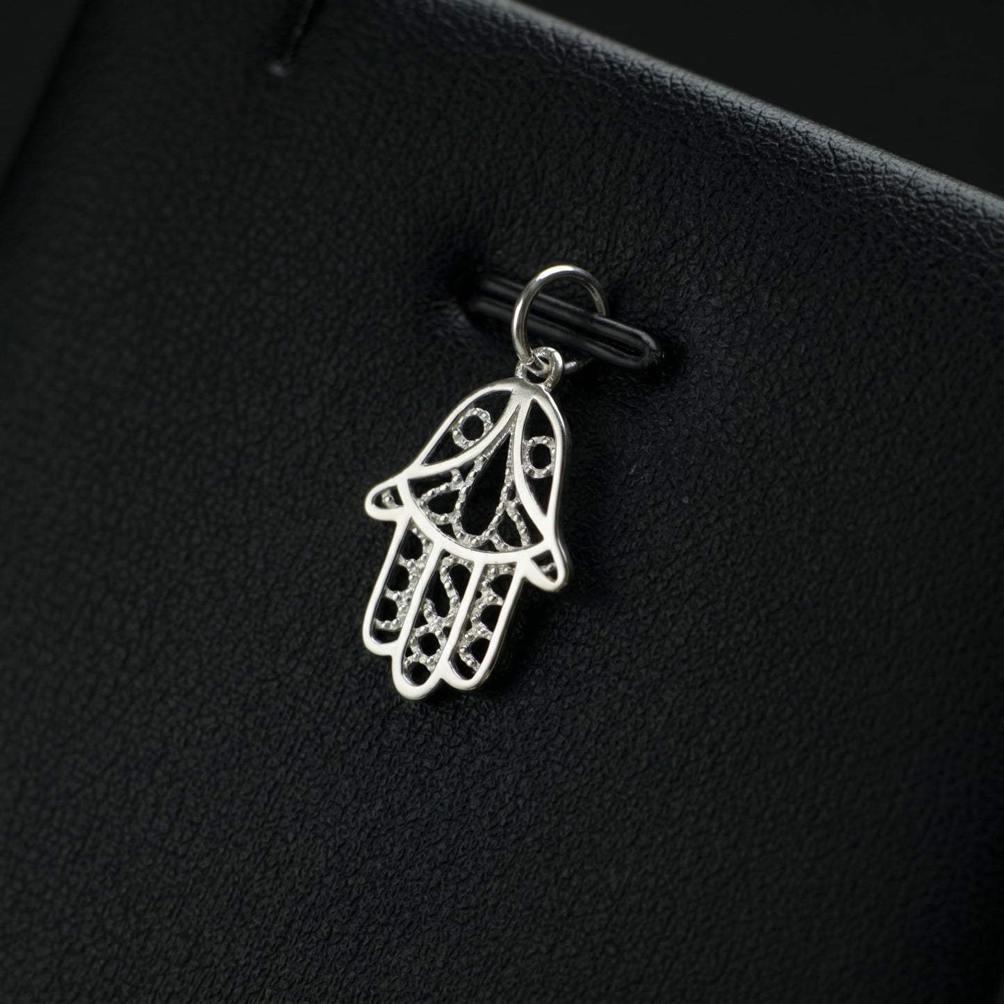 Silver hamsa hand charm pendant with detailed outline and textured filigree