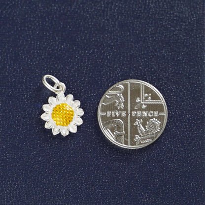 Silver sunflower charm with yellow center, shown with a coin for size