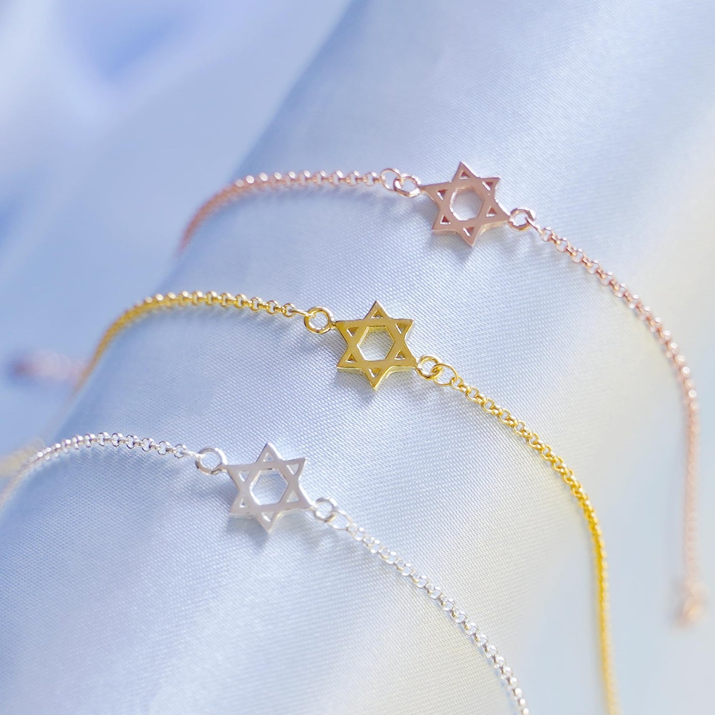 Stacked Star of David charm bracelets in silver, gold, and rose gold tones