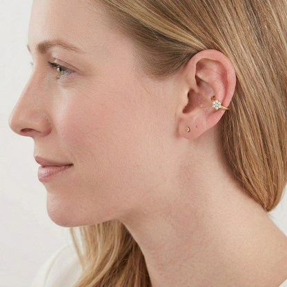 Silver CZ floral cuff hoop earring on ear, with a small flower cluster.