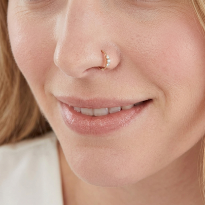 Silver CZ hoop ring with small flower cluster, worn on the nostril.