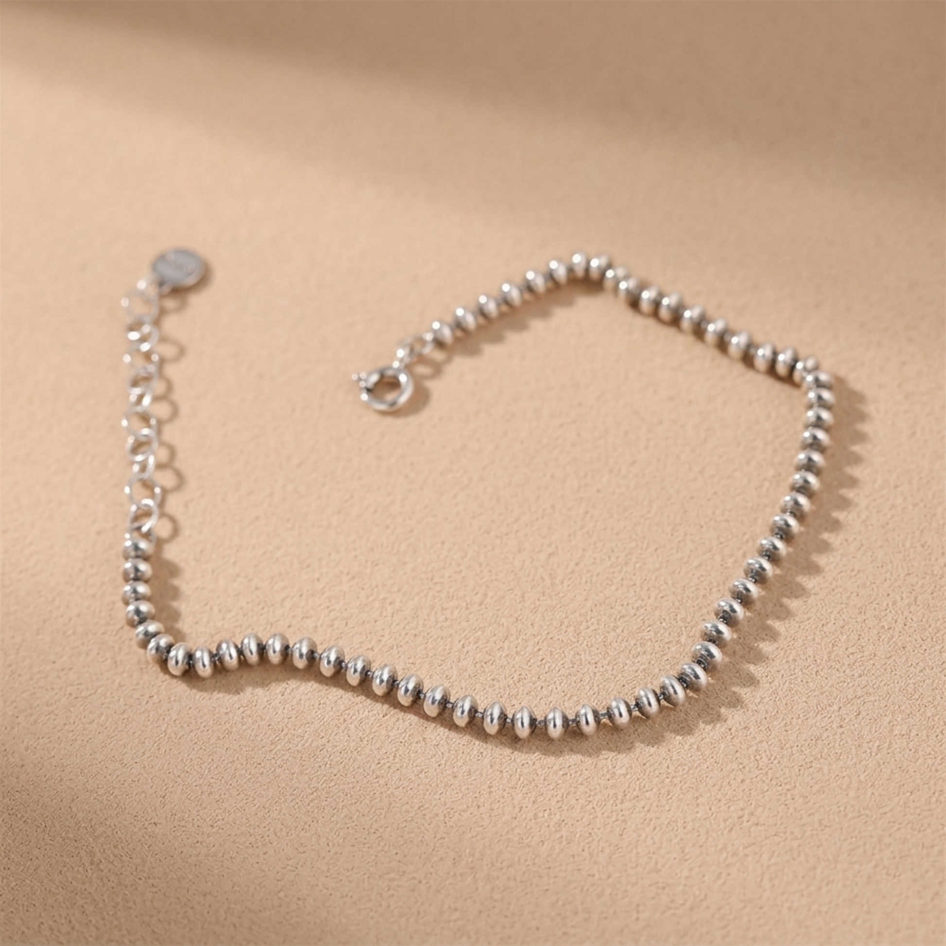 Silver-tone flat bead bracelet, round clasp at end on hand