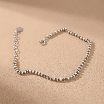 Silver-tone flat bead bracelet, round clasp at end on hand