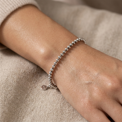 Silver-tone flat bead bracelet on wrist with round clasp